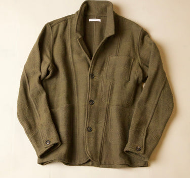 An olive green wool-blend work jacket with a button-up front, laid flat against a light beige background.