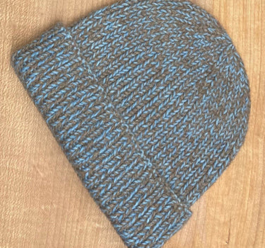 Knitted beanie with medium blue and brown pattern on a wooden surface