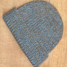Knitted beanie with medium blue and brown pattern on a wooden surface