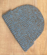 Knitted beanie with medium blue and brown pattern on a wooden surface